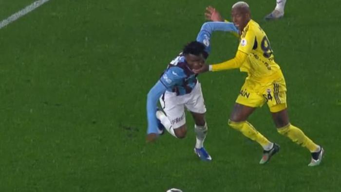 TALISCA'NIN YAPTIĞI MÜDAHALEDE İKİNCİ SARI KART GEREKİR Mİ?
Bahattin Duran: El Trabzonsporlu oyuncunun yüzüne geliyor. Gözüne ve yüz bölgesine. Bu hareketin karşılığı kontrolsüz hareketten dolayı ikinci sarı kart. Ancak burada yardımcı hakem pozisyonda ofsayt bayrağını geç kaldırmasaydı bu pozisyon olmazdı. Deniz Çoban: Burada bayrak zamanında kalksa iş buraya gitmezi. Talisca burada düdüğü duymayınca eyvah atıldım diyor. Ofsayt mı ofsayt. Ama oyun ofsayt olsun ya da olmasın bu hareket çok net kontrolsüz hamle. Talisca'nın burada ikinci sarı karttan oyundan ihraç edilmesi gerekiyordu. Bülent Yıldırım: Bence de net bir ikinci sarı kartlık kontrolsüz hamle.